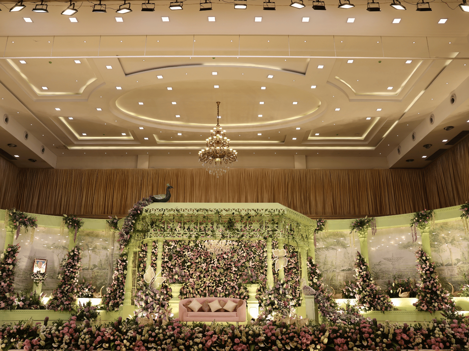 Champagne reception stage with chandeliers and lavender floral arches